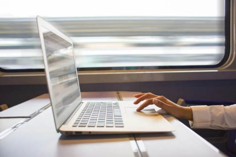 Close up woman hands typing on a laptop keyboard in the train